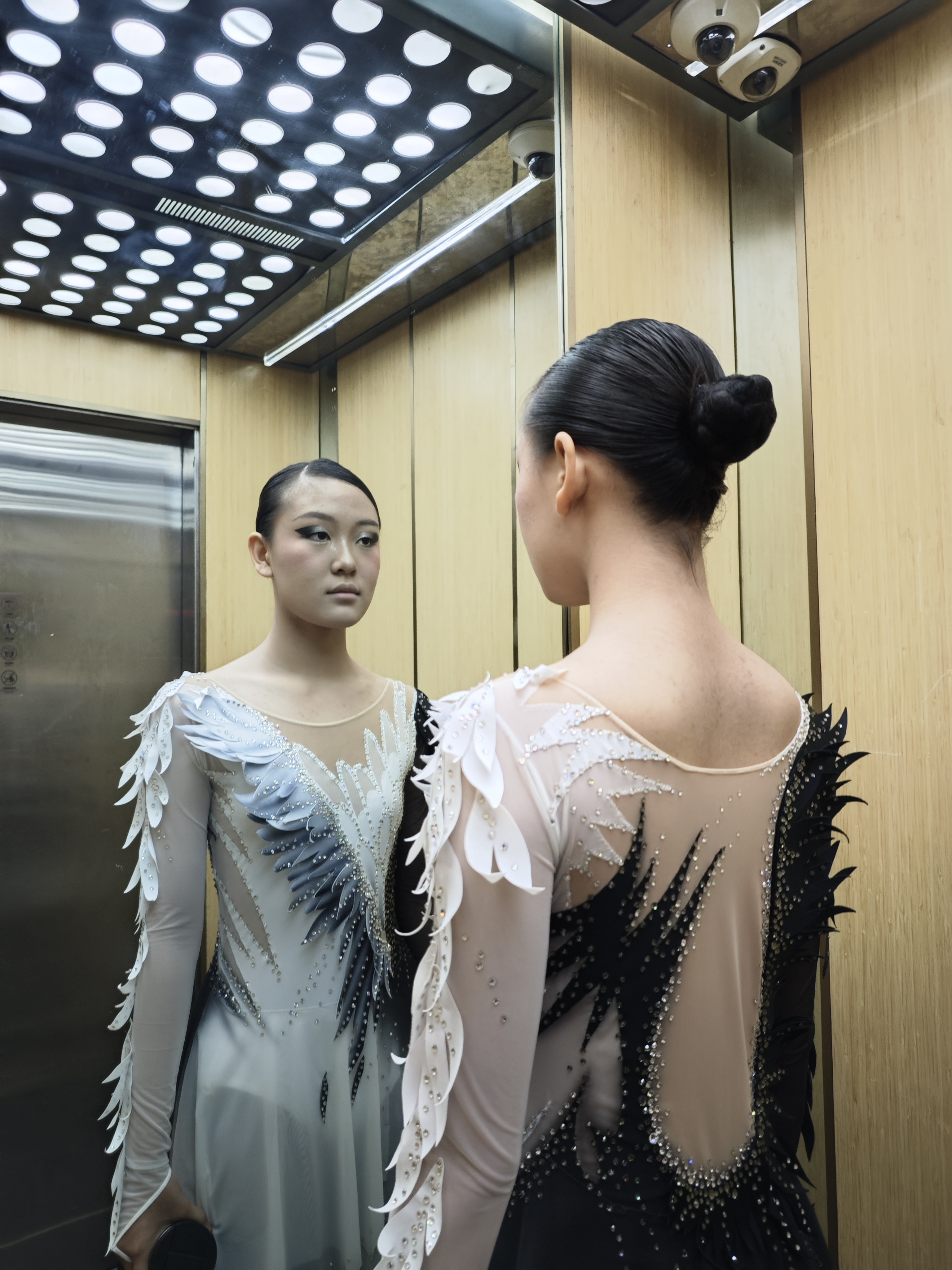 Martina Jiang in skating costume looking into a mirror before a performance